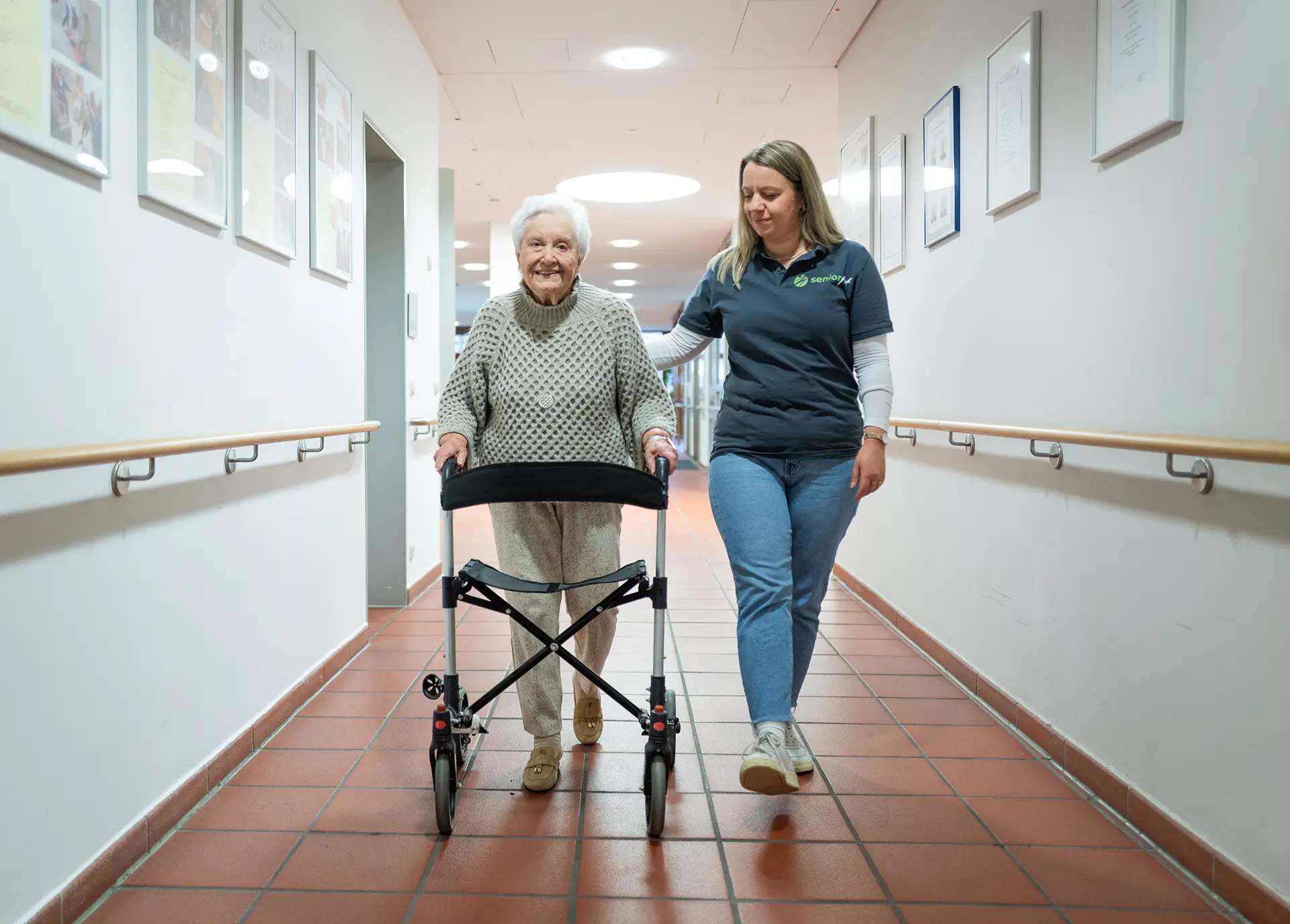 SeniorFit-Trainerin begleitet Bewohnerin mit Rollator beim Mobilitätstraining